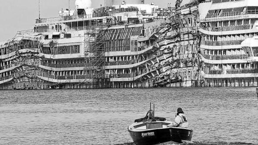 Un hombre navega cerca de los restos del &#039;Costa Concordia&#039; en el puerto de Giglio (Italia).