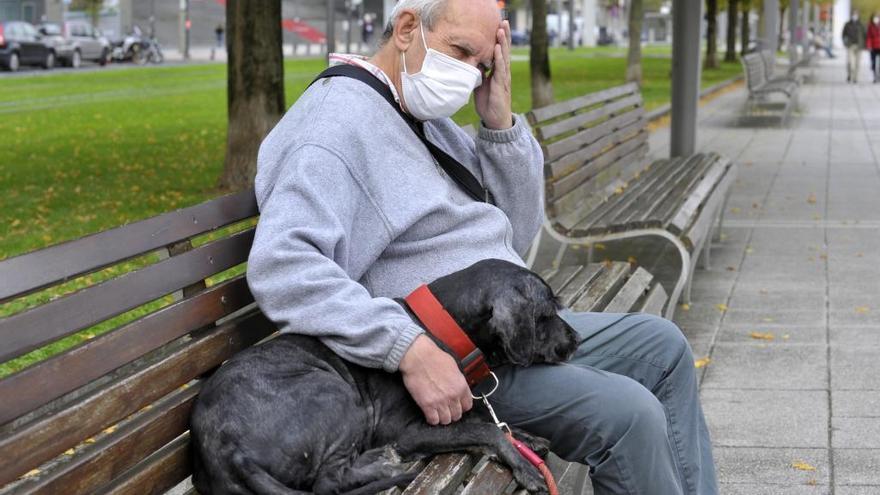 Un hombre descansa en un banco junto a su mascota.