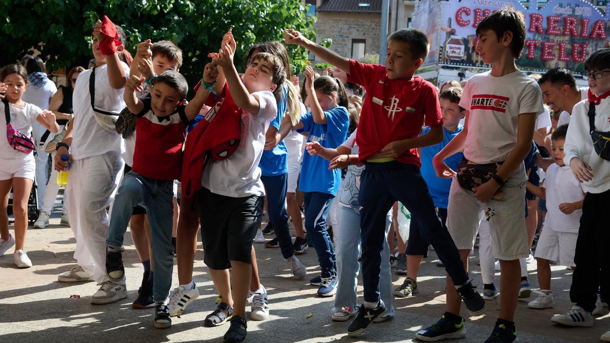 Los txikis de la localidad intentan coger los caramelos que lanzan desde el balcón del ayuntamiento.