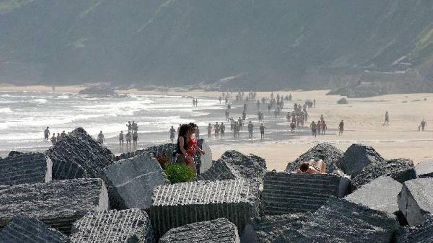 Decenas de personas pasean por la playa de Deba en una jornada veraniega de buen tiempo.