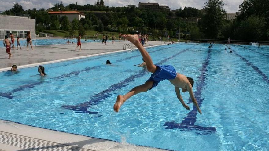 Niños saltando al agua en las piscinas de Aranzadi tras la apertura de la temporada de verano.