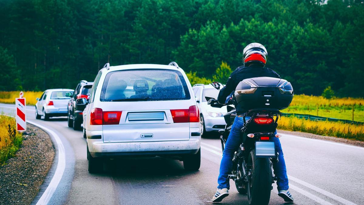 Una moto circula por la carretera detrás de varios coches.