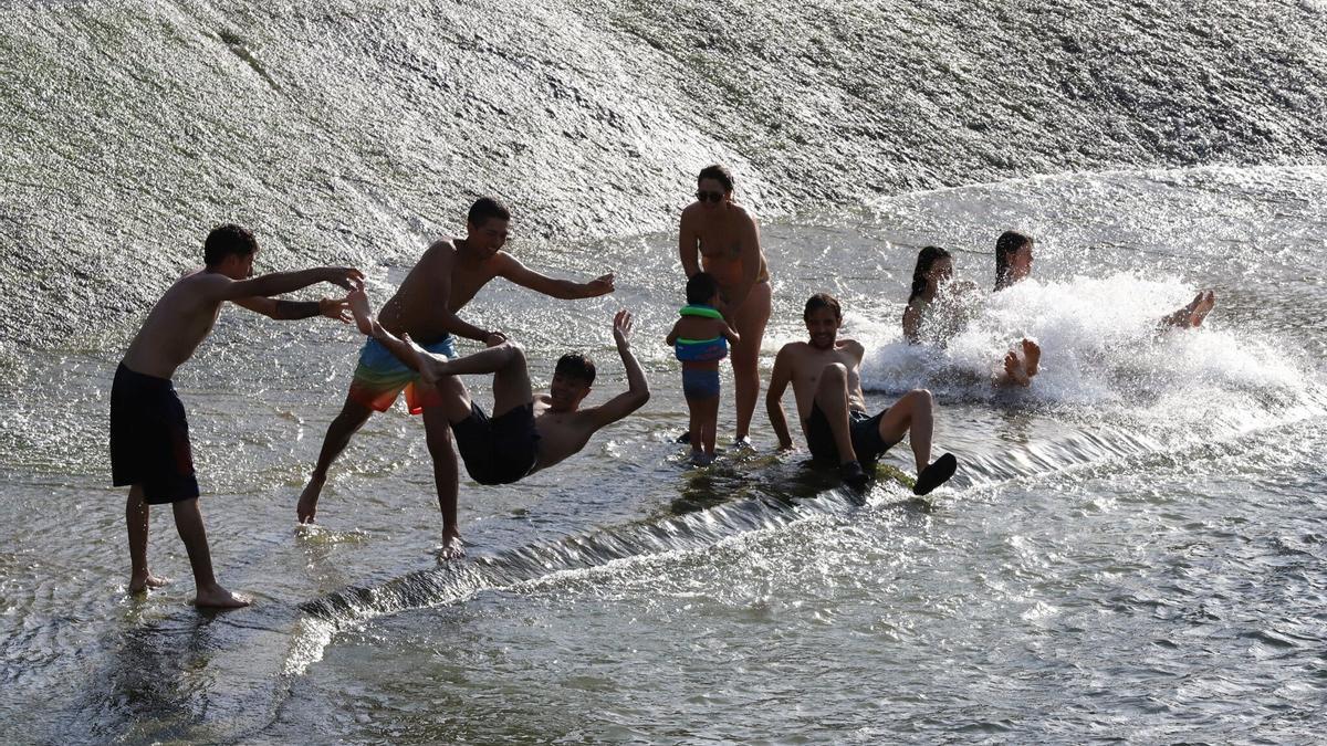 Varias personas se bañan en el río Arga.