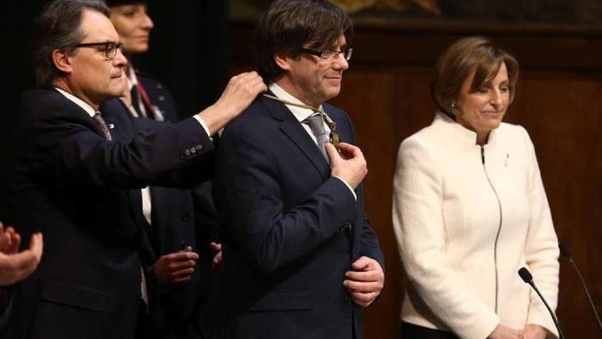 El expresidente de la Generalitat, Artur Mas (i), impone la medalla representativa del cargo al nuevo presidente de la Generalitat, el independentista Carles Puigdemont.