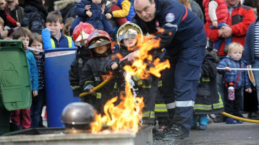 Un bombero enseña a varios niños ataviados con trajes ignífugos cómo se maneja la manguera para apagar un fuego, durante la jornada de ayer en Bilbao.