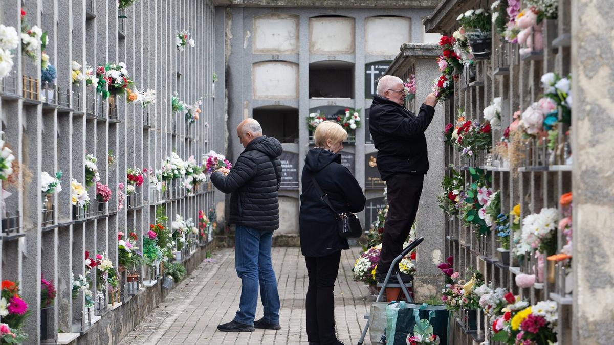 Varias personas visitando los nichos de sus seres queridos decoradas para Todos los Santos.