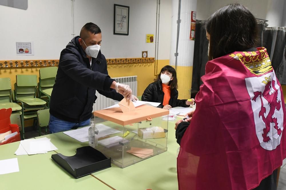 Una joven con una bandera de León atada a su cuello vota en el colegio electoral instalado en la guardería municipal de Cistierna (León) este domingo.