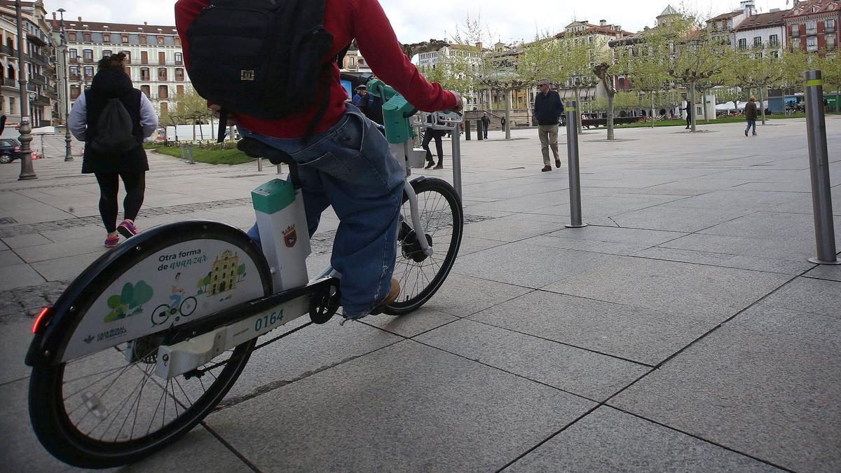 Un joven en bicicleta eléctrica por la plaza del Castillo de Pamplona.