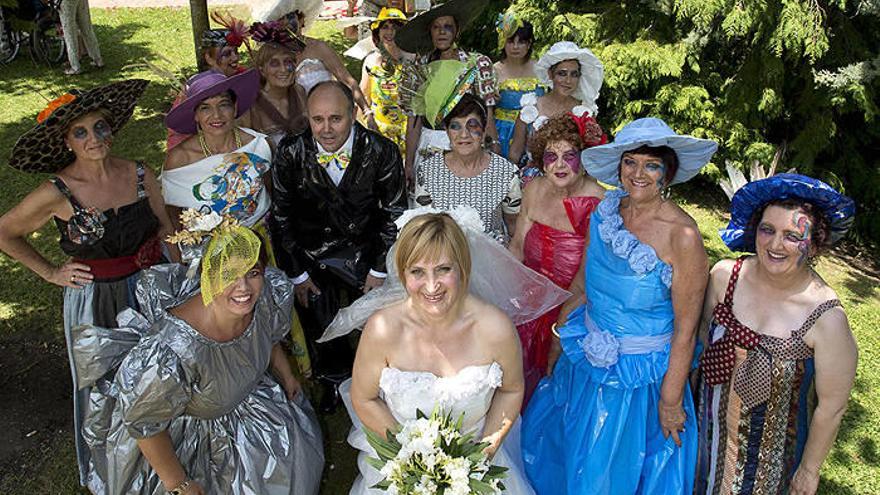 Las 16 personas que han trabajado en la elaboración de vestidos y trajes con materiales reciclados. En el centro, con traje de novia, Mª Carmen Iradiel, la diseñadora.