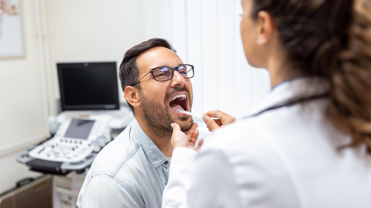 Una médico explora la garganta de un paciente