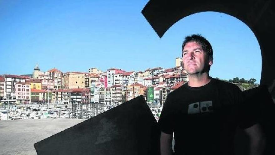 Jabier Elortegi posa bajo la escultura de Nestor Basterretxea &#039;Olatua&#039;, con el puerto deportivo de Bermeo al fondo.