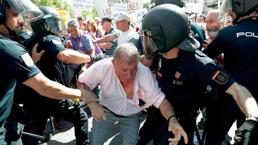 Varios jubilados forcejean ayer con policías al intentar empujar las vallas que rodean el Congreso.Foto: Efe