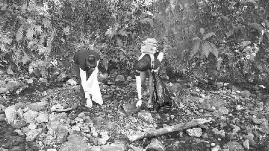 Dos integrantes del colectivo ecologista Eguzki recogiendo la basura encontrada en Leitzaran el pasado domingo.