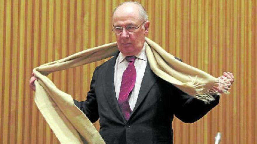 Rodrigo Rato se quita su bufanda antes de comparecer en el Congreso de los Diputados.