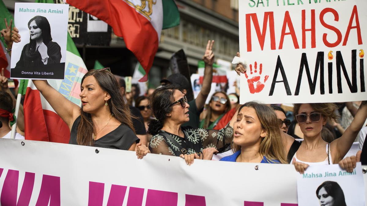 Manifestantes sostienen pancartas y fotografías de Mahsa Amini durante una marcha en su memoria en Roma.
