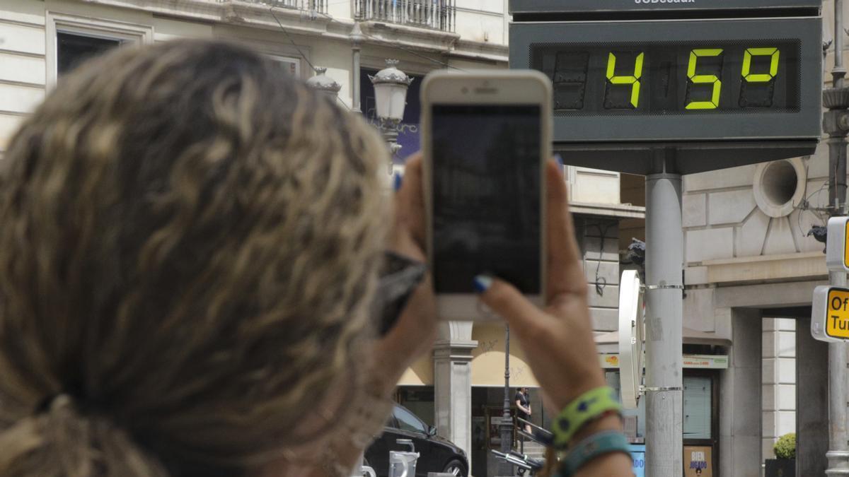 Una mujer fotografía la temperatura de un termómetro que marca 42 grados.