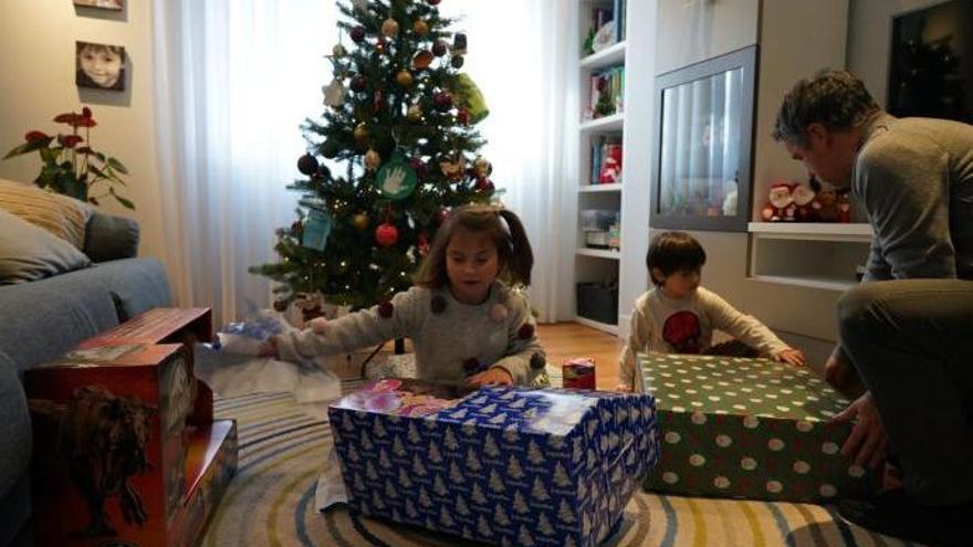 Dos niños desenvolviendo regalos de Navidad.