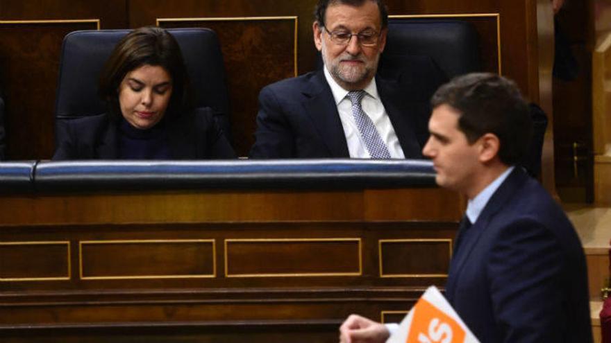 El presidente de Ciudadanos, Albert Rivera, cruza ante Mariano Rajoy y Soraya Sáenz de Santamaría, en un pleno del Congreso.