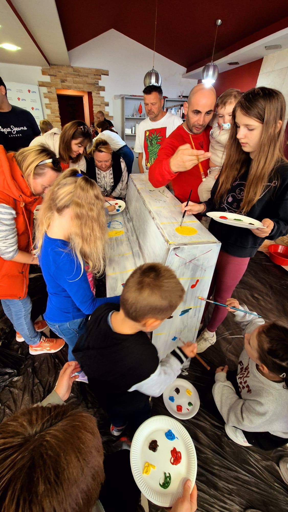 Niñas y niños ucranianos refugiados, pintando el piano que se subastará en el festival 'Sueña Bailando'.