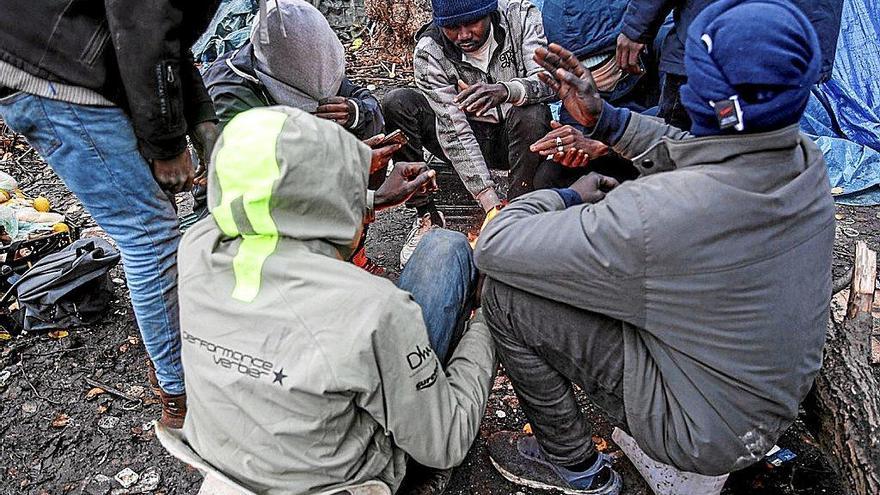 Un grupo de sudaneses se calienta con un hoguera en un campamento improvisado en Calais. Foto: Efe