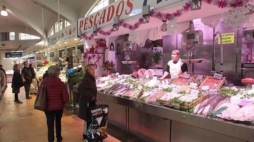 Varias clientas contemplan el género en una pescadería del mercado del Ensanche.