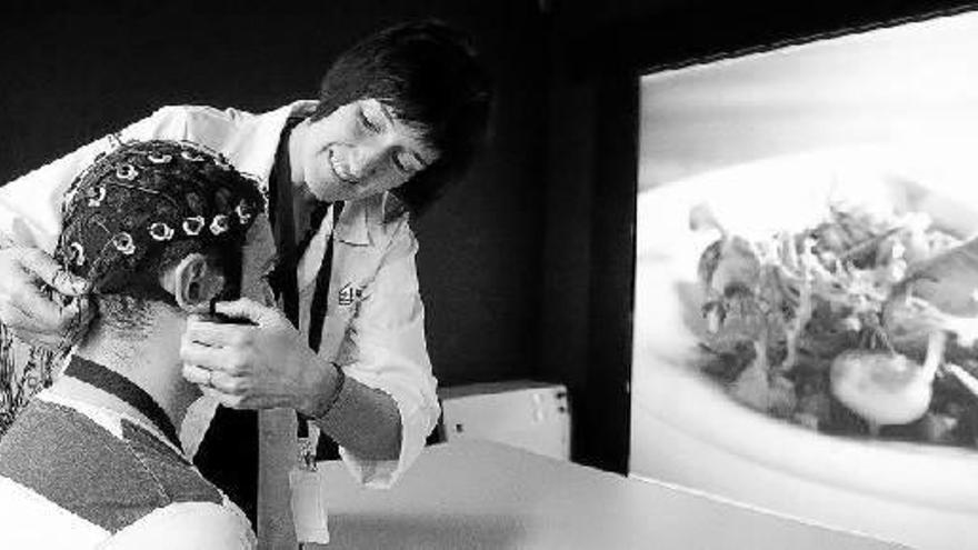 Una investigadora coloca el casco neuronal de la sala de neurogastronomía del centro.