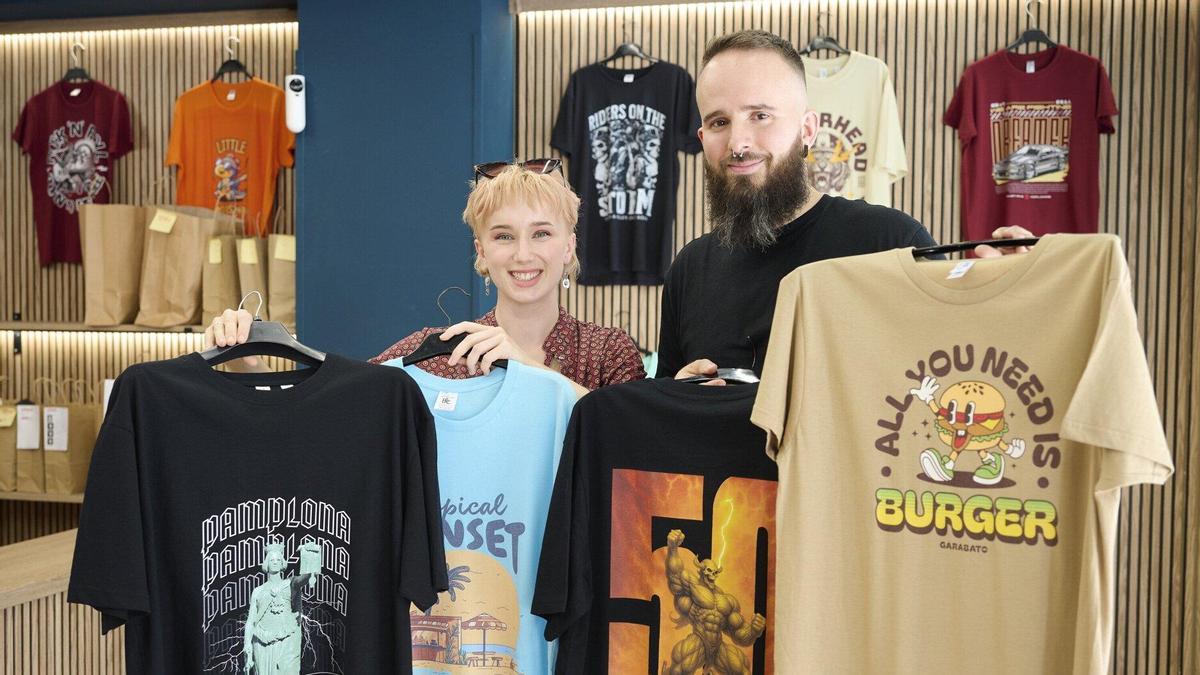Kamila e Iker, propietarios de la tienda de la calle Esquíroz, posan con una de las estrellas de su catálogo, las camisetas personalizadas.