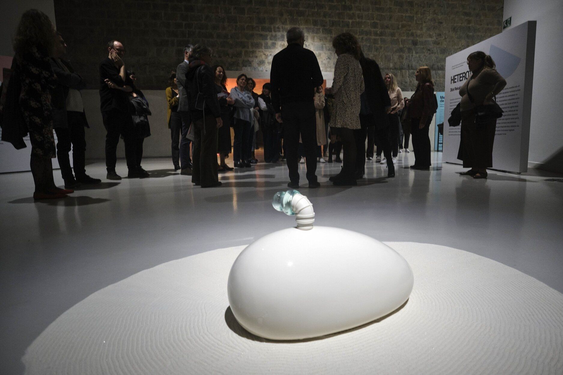 Asistentes a la presentación de la exposición, en la Sala de la Muralla de Baluarte y, en primer término, una obra de Dick Rekalde.