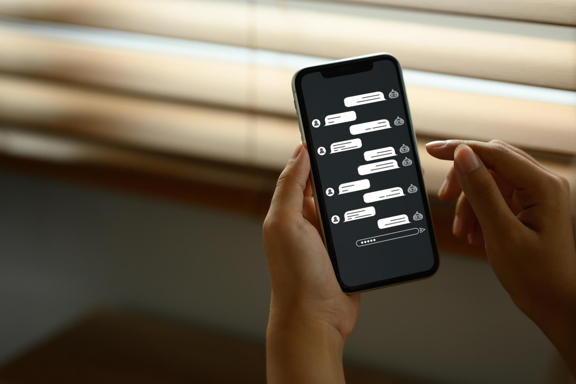 Una mujer interactúa con un chatbot conversacional en el móvil.