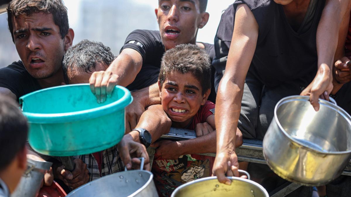 Palestinos esperan recibir comida en un campamento para desplazados.