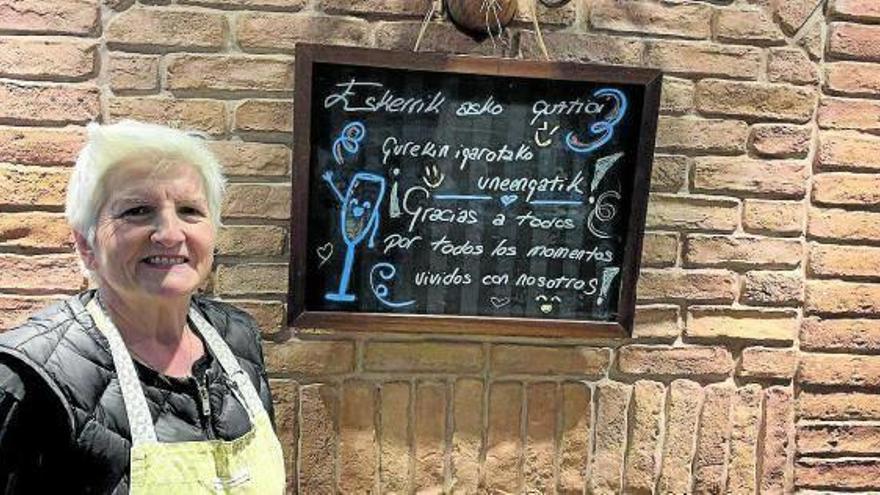 Mertxe Aizpurua posa dentro del bar con el dibujo de agradecimiento para la despedida.
