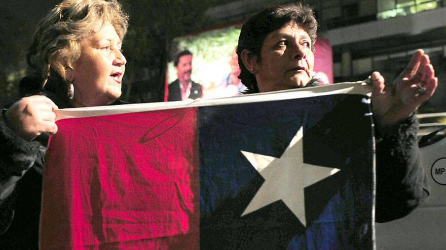 Dos mujeres sostienen una bandera chilena frente a las oficinas de Televisión Nacional de Chile (TVN), en una manifestación espontánea.