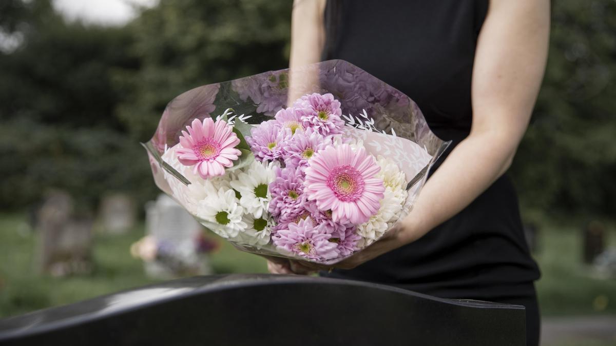Una persona llevando flores al cementerio, en una imagen de archivo.
