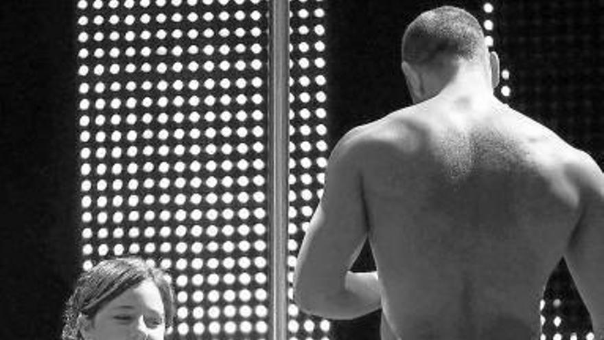 Una mujer observa a un hombre semidesnudo en un espectáculo.