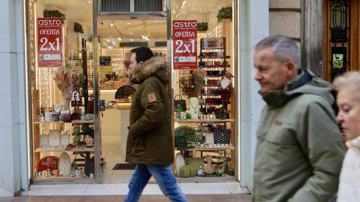 Imagen de unos viandantes pasando junto a una tienda en Vitoria-Gasteiz con descuentos.