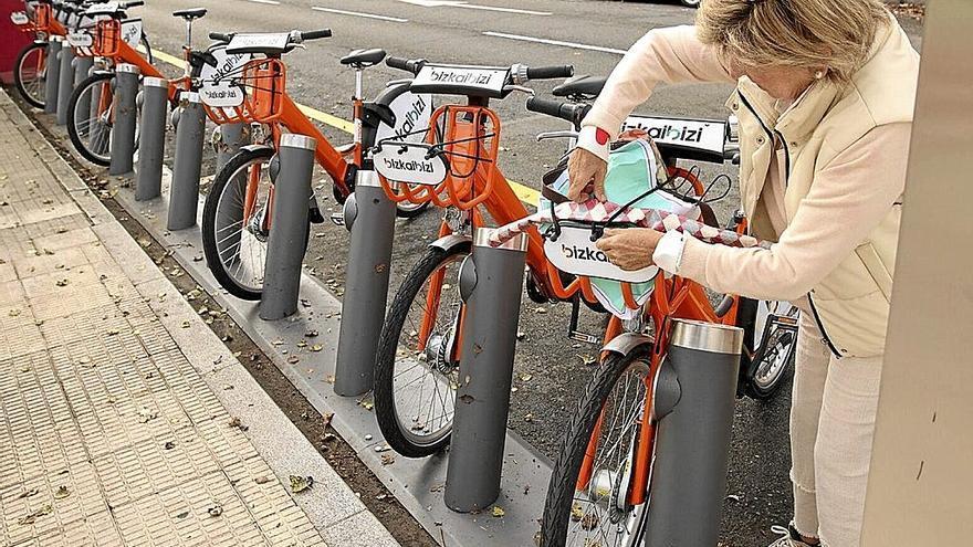 Una mujer retira una bicicleta de Bizkaibizi en una de las estaciones de anclaje de Bilbao.