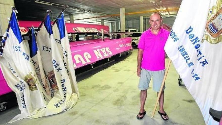 Juan Mari Etxabe posa en las nuevas instalaciones del club con la Bandera femenina de La Concha conquistada el domingo en la mano y las otras cuatro, logradas como remero en los años 80 y 90, sobre uno de los botes rosas de San Juan.