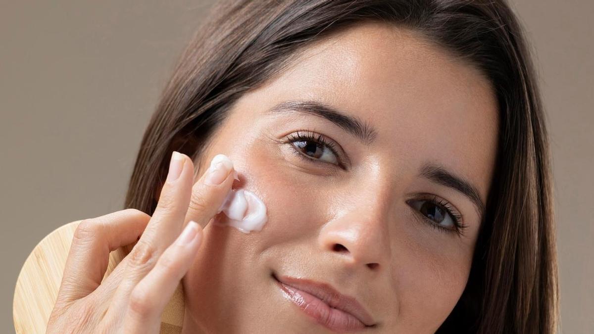Una mujer se aplica crema hidratante en el rostro. Una mujer se aplica crema hidratante en el rostro.