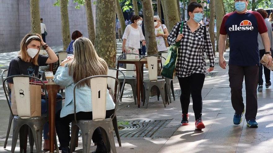 Varias personas sentadas en la terraza de un bar con mascarilla.