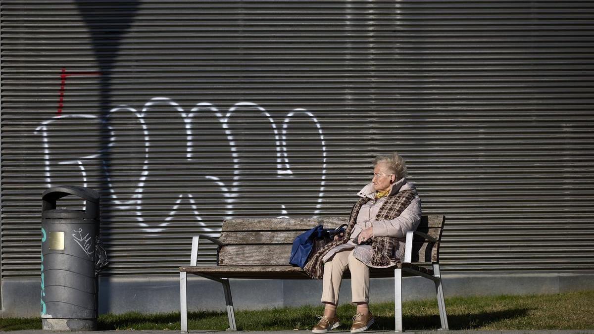 Una mujer descansa en un banco de Azpilagaña.