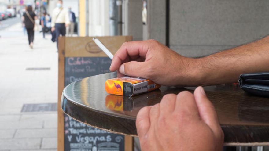Un hombre fumando en el exterior de un bar.