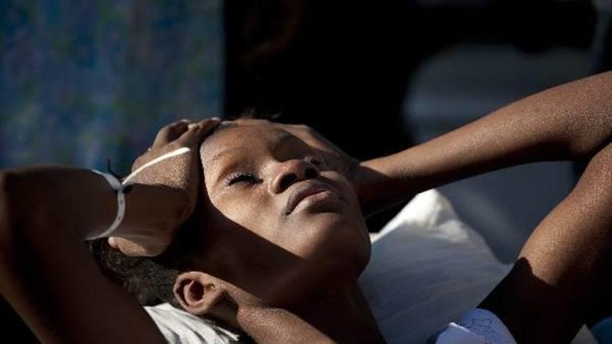 Una mujer con síntomas de cólera se toca la cabeza mientras permanece en una carretilla, ayer en un hospital de Puerto Príncipe (Haití).