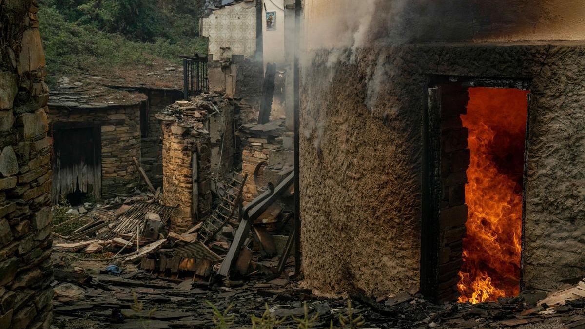 Vista de viviendas ardiendo en la aldea de San Vicente, este lunes en Vilamartín de Valdeorras (Ourense).
