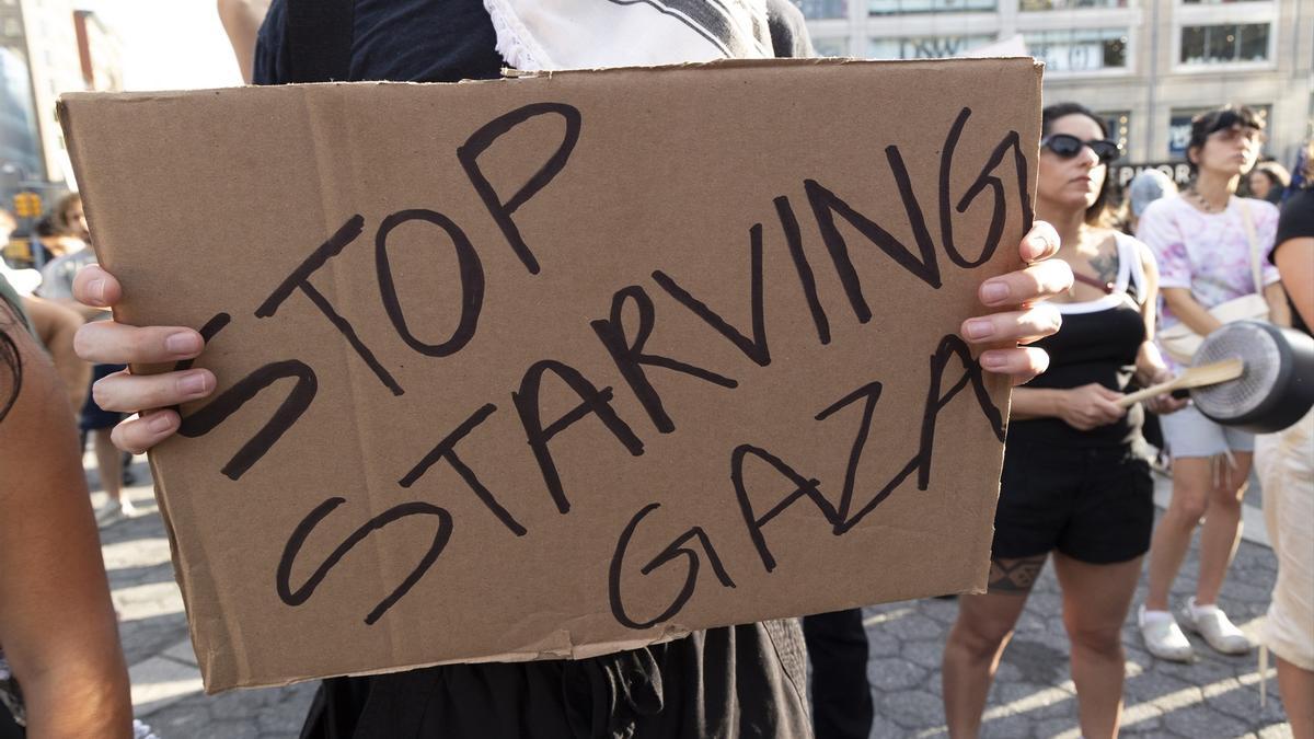 Un cartel clama contra la hambruna en Gaza: el hambre se ha convertido en un arma de guerra por parte de Israel desde el inicio de la ofensiva tras el ataque del 7-O.