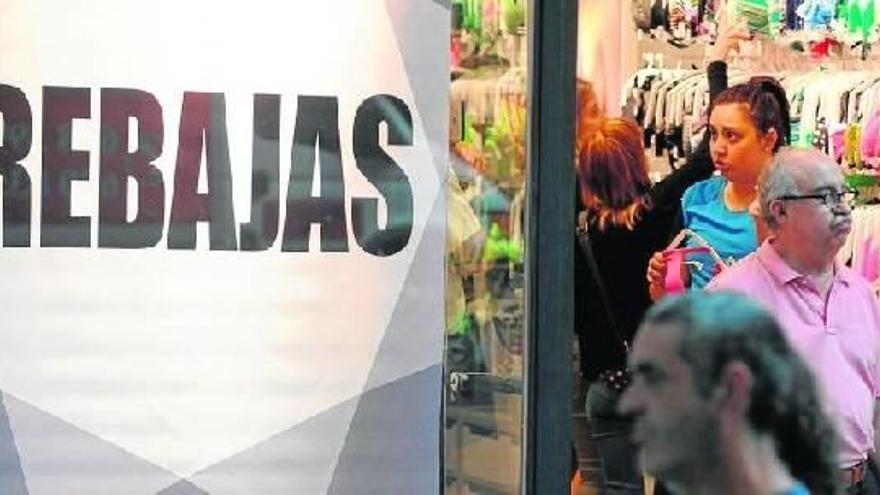 Un cartel anuncia los descuentos mientras varias personas miran artículos de ropa de baño.
