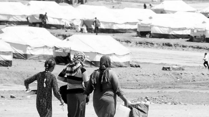 Tres mujeres se dirigen a recoger agua en un campo de refugiados del norte de Irak.