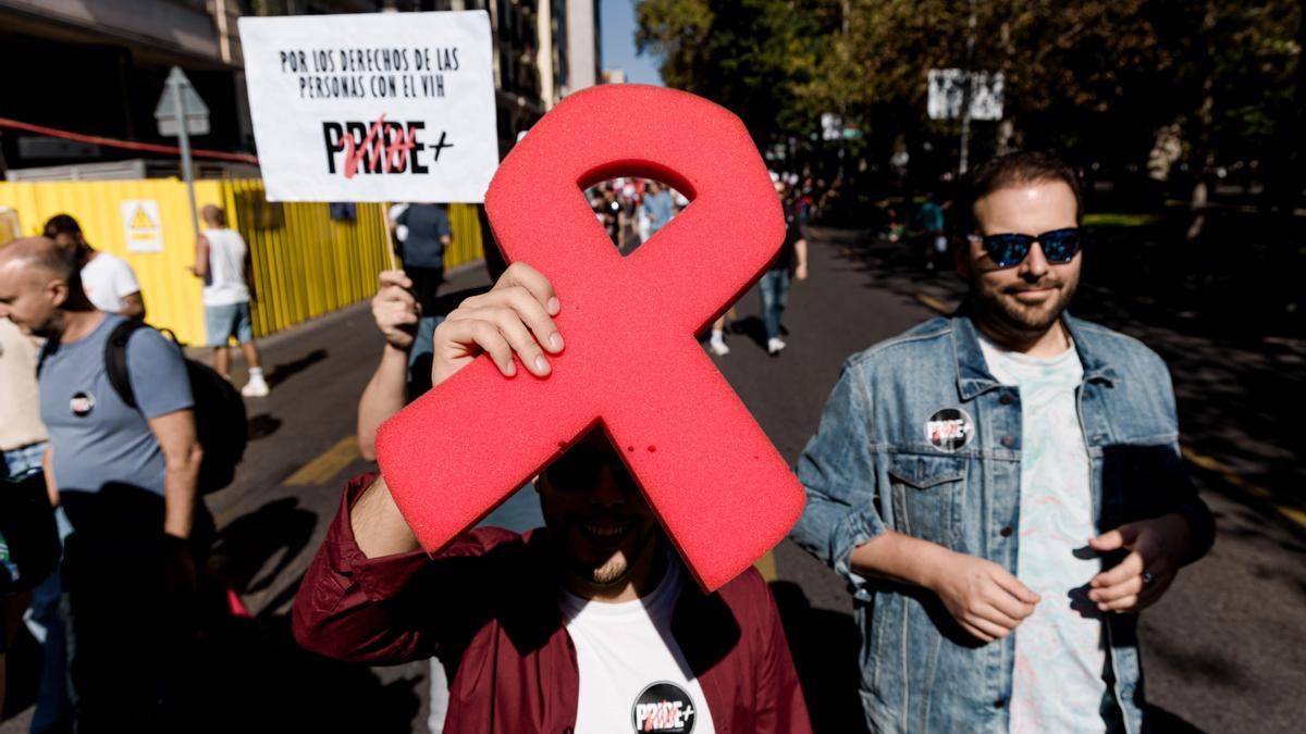 Manifestantes portan un lazo rojo y pancarta con lema &#039;Por los derechos de las personas con VIH&#039;