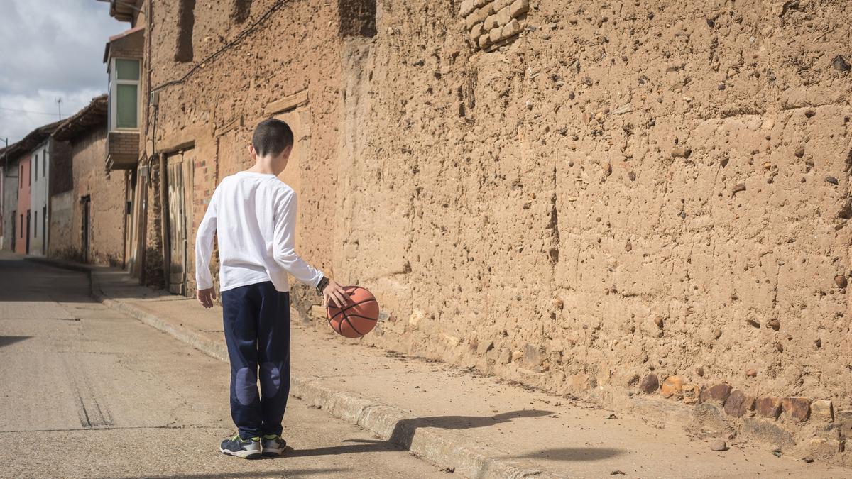 Un niño juega al balón en un pueblo