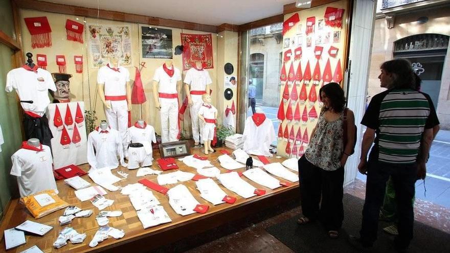 Varias personas mirando un escaparate de San Fermín.