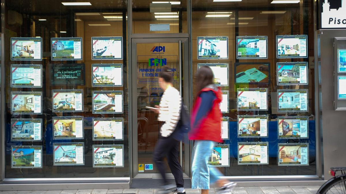 Dos personas observan la fachada de una inmobiliaria en el centro de Vitoria